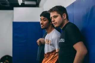 Justin observing two students practising a submission, offering corrections